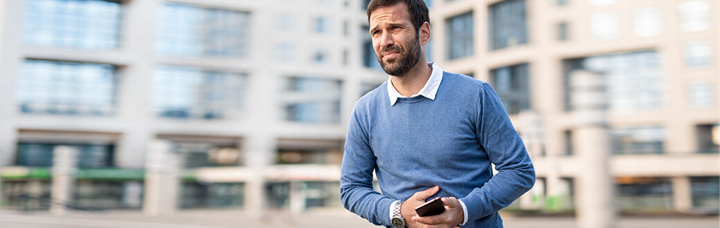 A man holding his belly in discomfort.