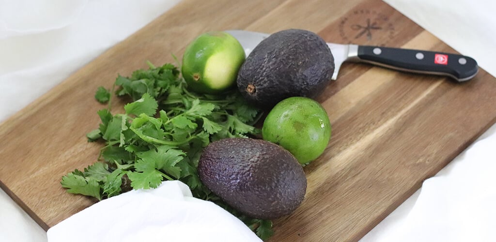 avocado, lime, and cilantro on a cutting board