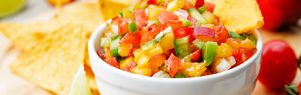 Fresh Peach Pico De Gallo in a bowl served with chips.