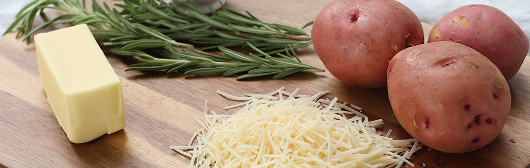 Rosemary, Potatoes, and shredded Parmesan on a cutting board.