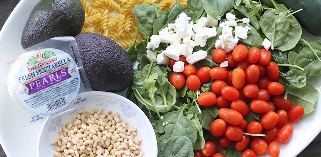greek salad ingredients including avocados, mozzarella, pine nuts, cherry tomatoes and more