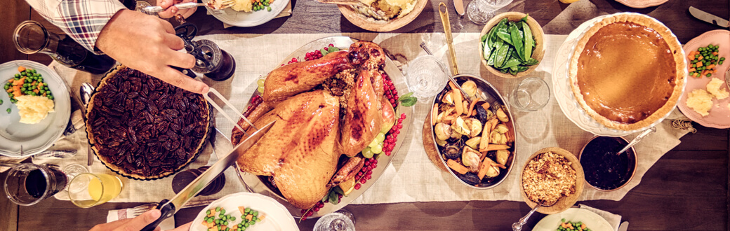 A dining room table with traditional Thanksgiving dishes on it.