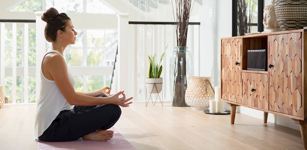 A woman meditating in her home.