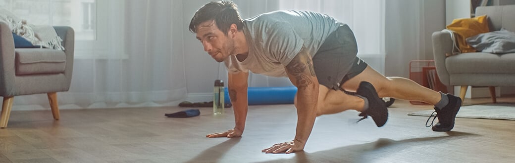 A man performing mountain climbers indoors.