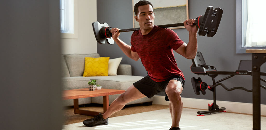 A man performing a barbell side lunge.