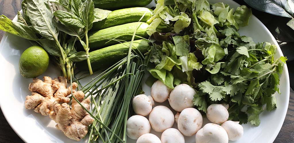 ginger, cilantro, cucumbers, chives and lime on a plate