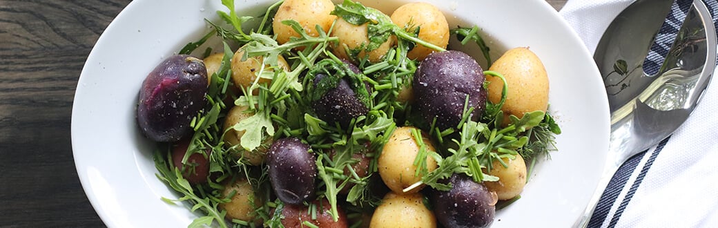 Lemon, arugula, and herb potatoes in a serving bowl.