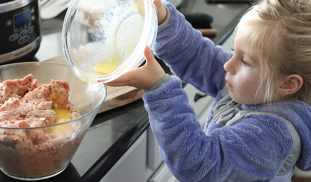A young girl making turkey meatballs