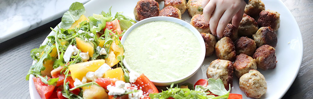 Greek chicken meatballs on a plate with Greek salad and dip.