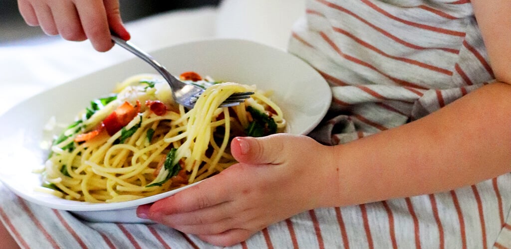 bacon arugula pasta in a white bowl