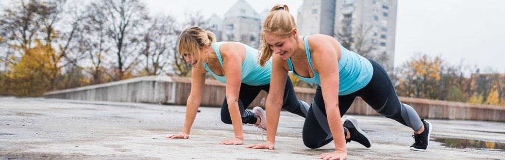Two women outside performing mountain climbers.