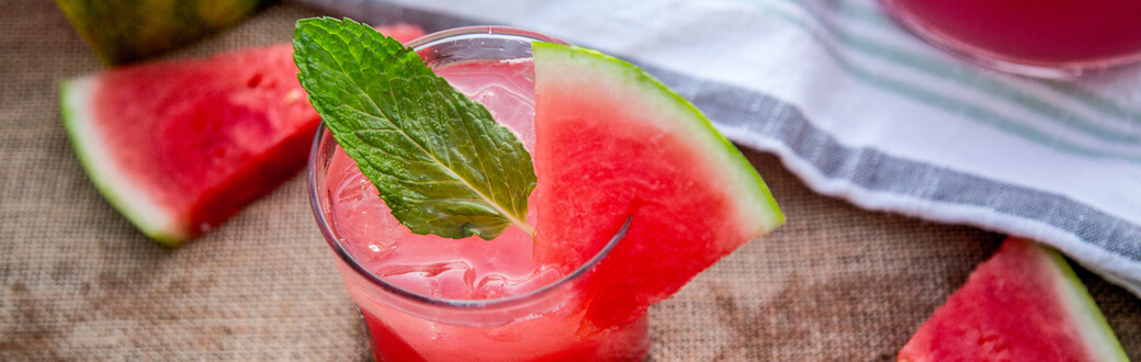 A glass filled with watermelon mojito mocktail. Garnished with mint and watermelon.