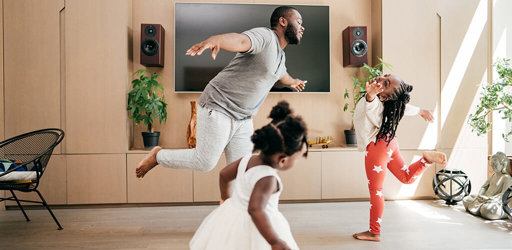 A man and two kids dancing in their living room.