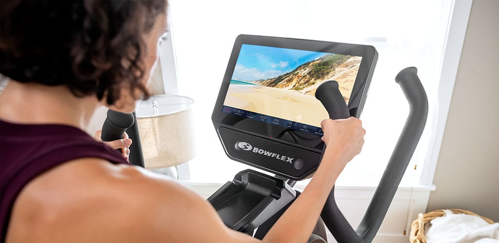 A woman on a Max Trainer using the Explore the World feature on JRNY.