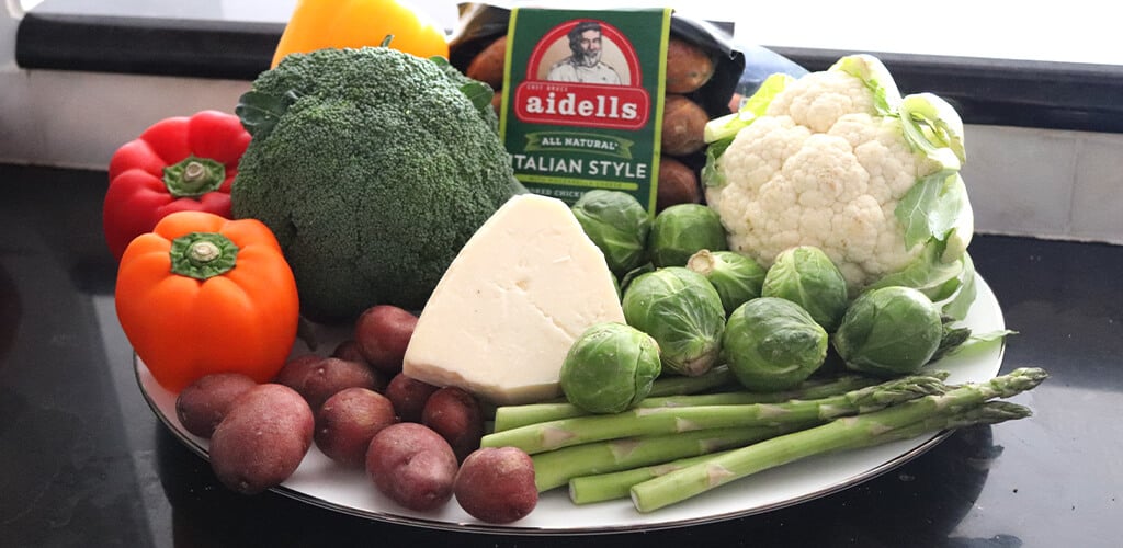 Assorted vegetables, sausage, and cheese on a plate.