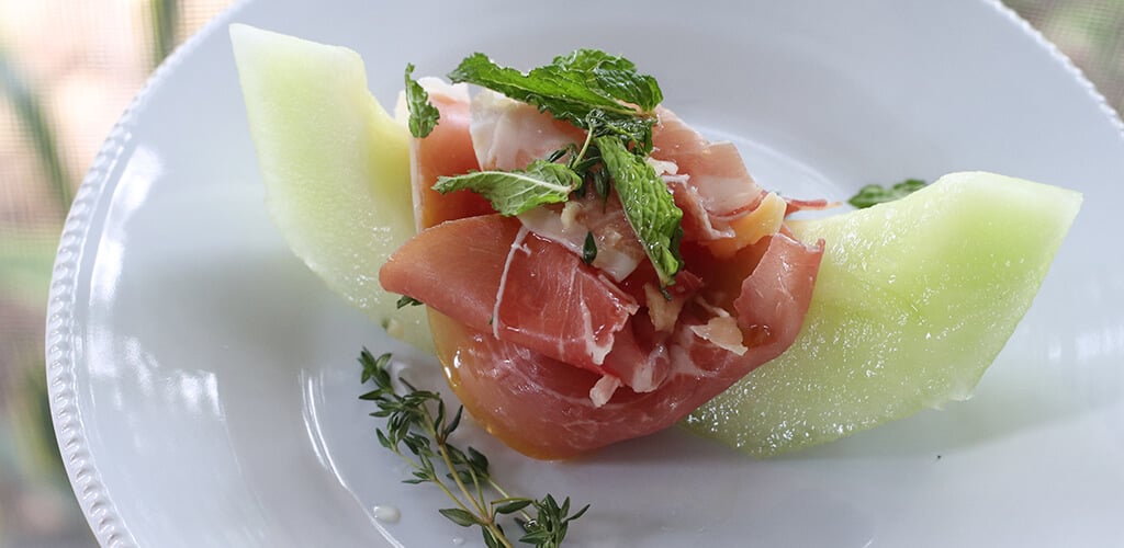 Prosciutto, parmesan, honeydew appetizer on a serving plate.