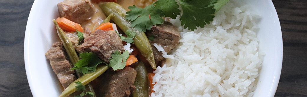 Beef curry and white rice on a plate.