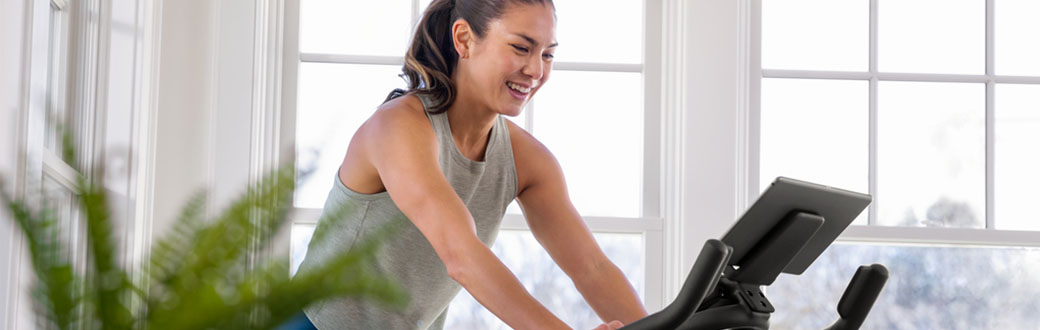 A woman using a BowFlex Indoor Cycling Bike.