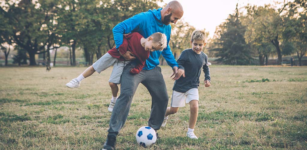 A man and children playing soccer outside.