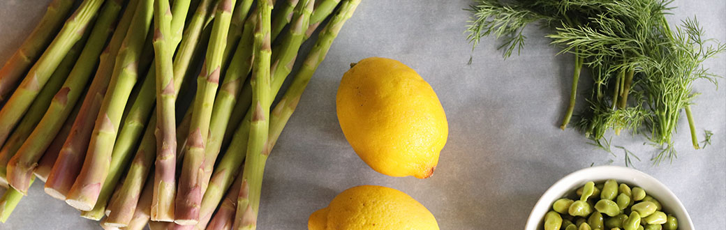 Asparagus, lemon, and herbs prepped on a cutting board.