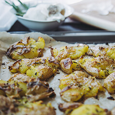 Cooked smashed potatoes on parchment.