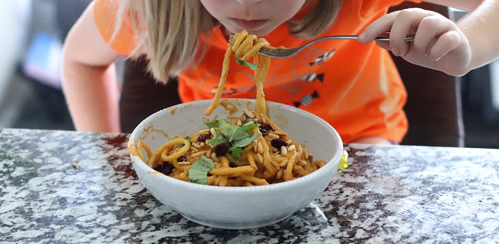 A child eating creamy pumpkin pasta