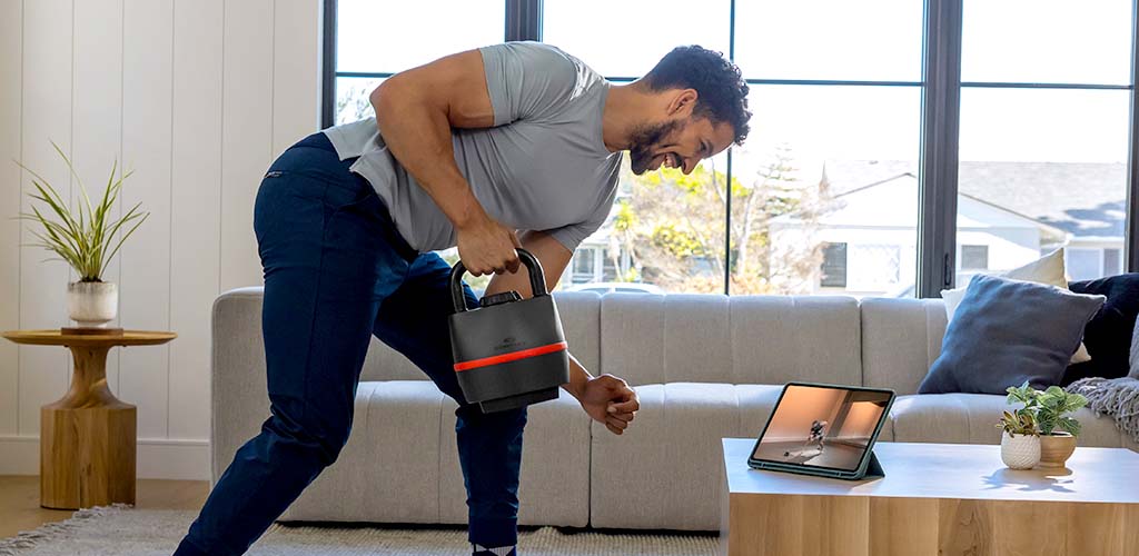 Man in a living room doing a kettlebell workout