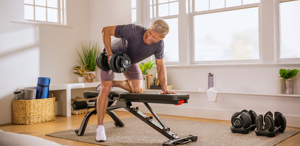man using a bowflex dumbbell and bench