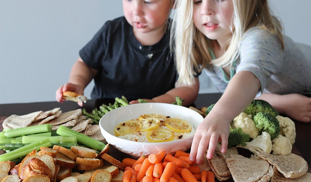 two kids eating lemon feta dip.