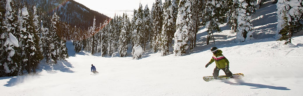 two people snowboarding downhill