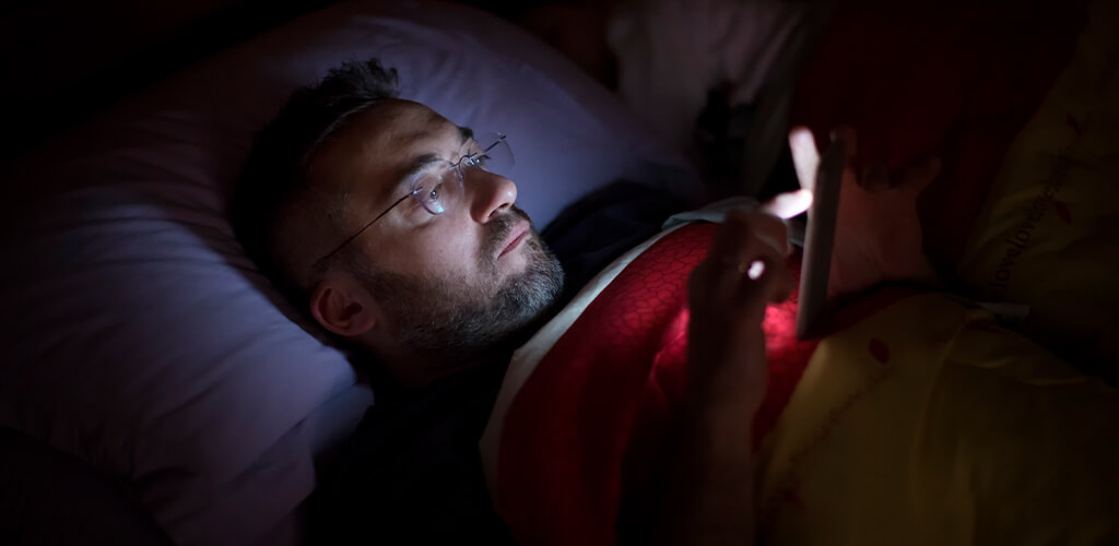A man using his phone in bed.