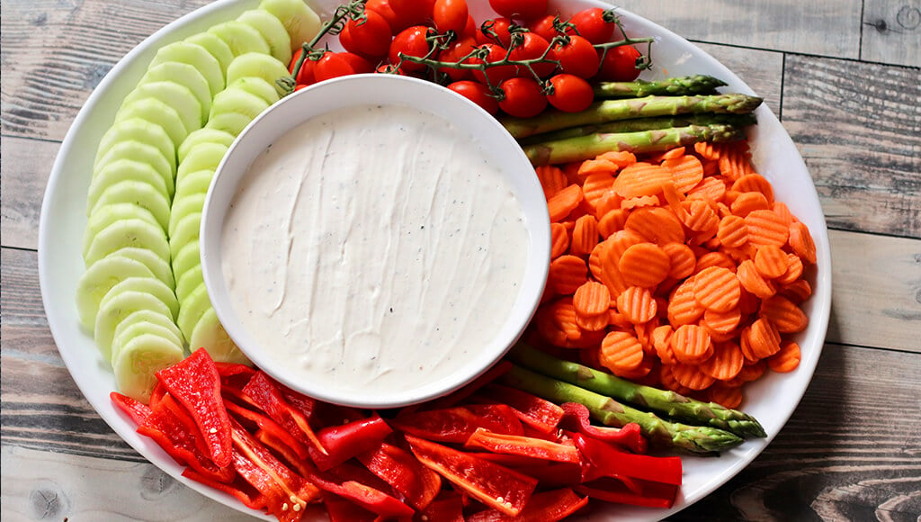 white truffle dip in a bowl surrounded by cut up veggies.