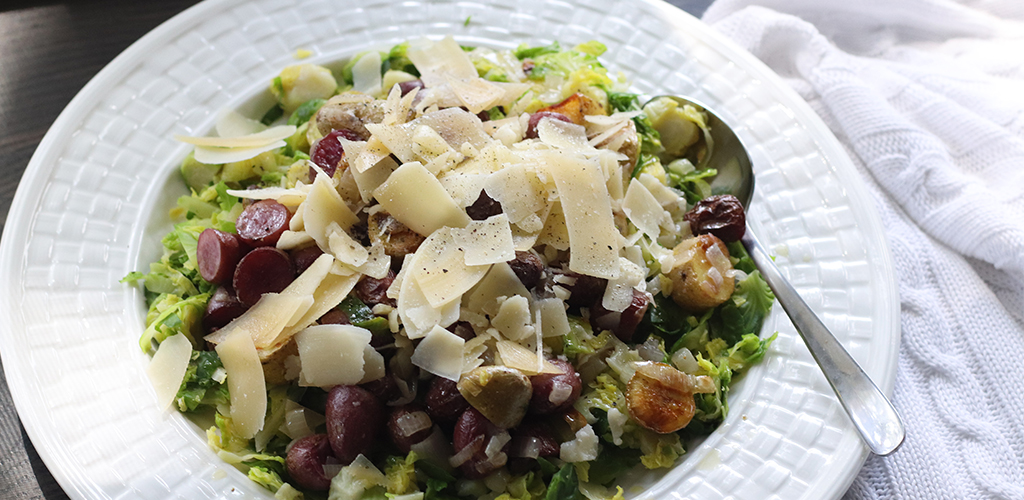 Roasted potato, shallot, and Brussels sprouts salad in a serving dish.