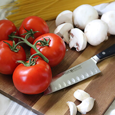 Tomatoes, garlic, and mushrooms on a cutting board.