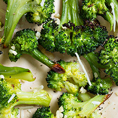 Closeup of roasted broccoli florets topped with Parmesan cheese.