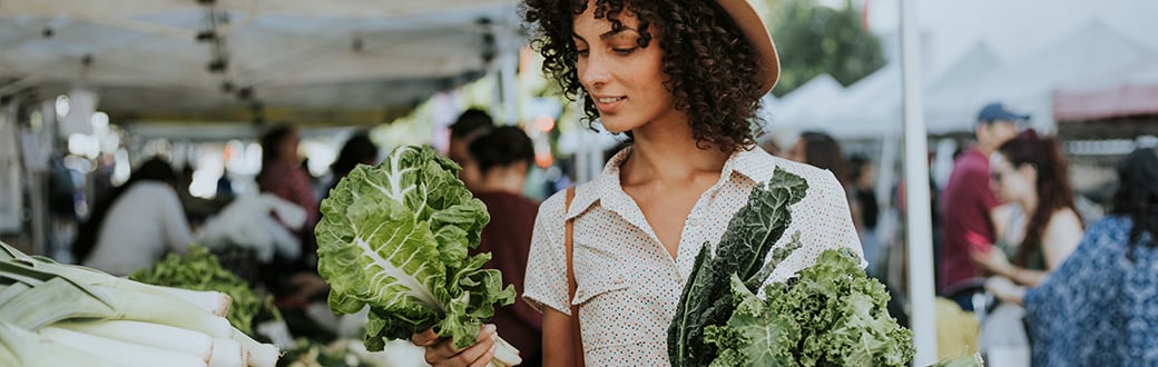 a woman looking at lettuce at a farmer's market